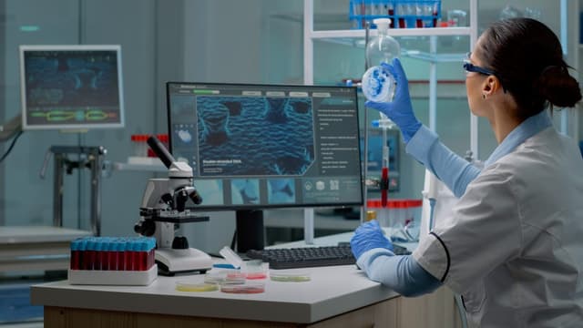 Innovation scientist studying petri dish with liquid bacteria